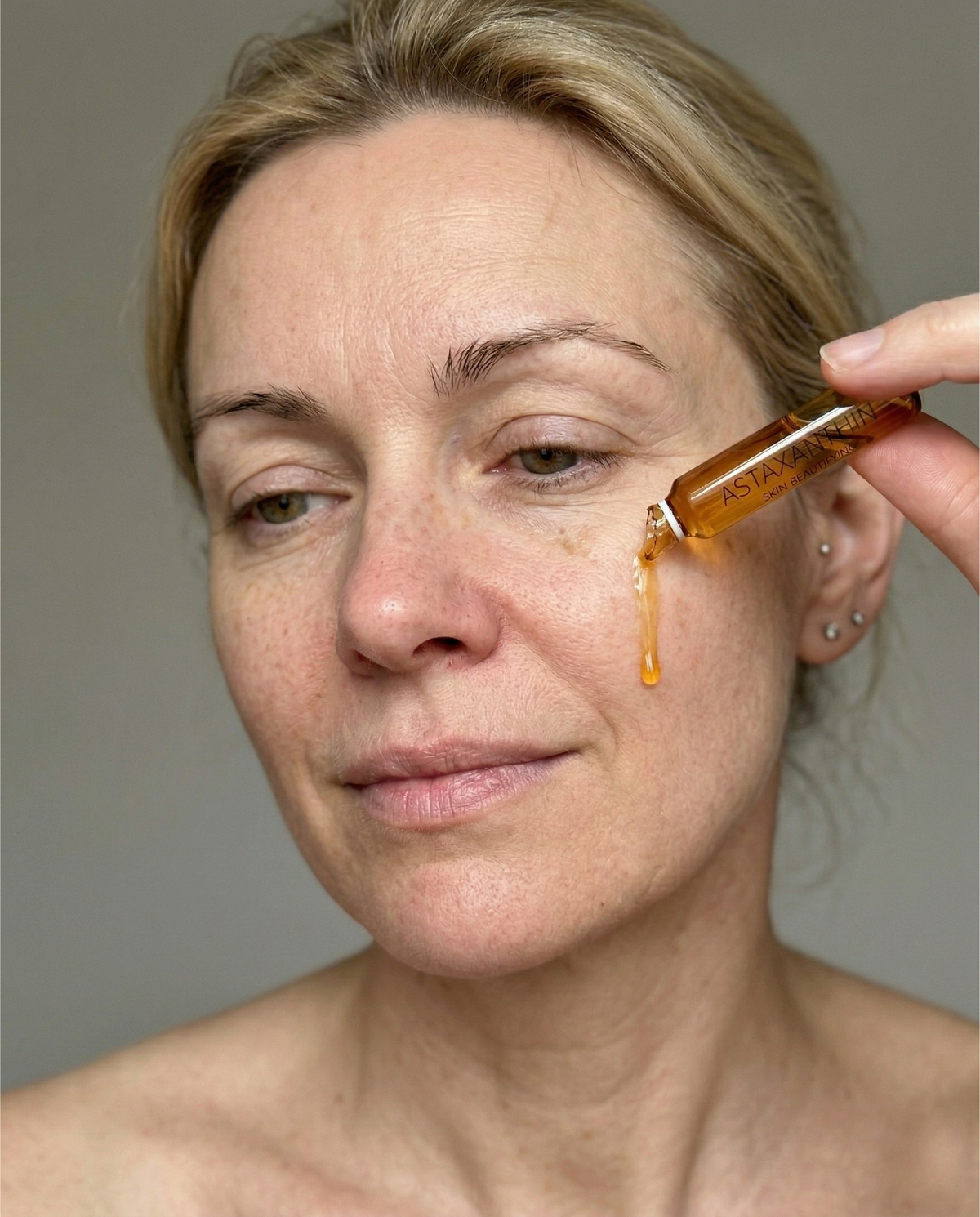 Woman applying Youthology ampoule serum